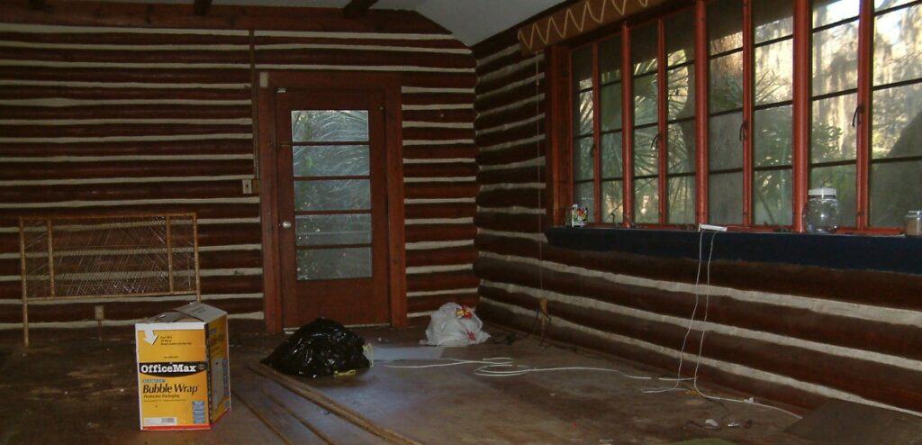 Our house gutted by the developers we sold to. My beautiful homestead made into a parking lot. This is a picture of our living room after we had left. It is showing the logs and cement filling painted white. Shows the old-fashioned solid, hand turning Florida windows, wooden floors and visible hand-hewn logs/braces on ceiling.